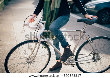 Close up on the legs riding a bike of young beautiful sporty woman in town - alternative methods of transportation, sportive concept