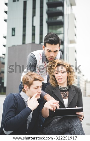 Multiracial contemporary business people working outdoor in town connected with technological devices like laptop, talking to each other watching the screen  - business, finance, technology concept