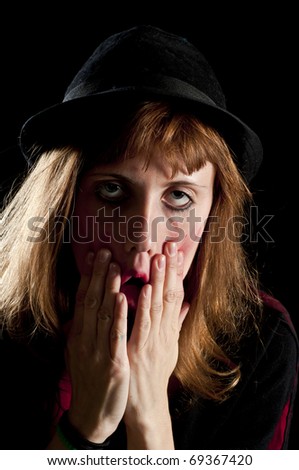 blonde girl deforms the face with his own hands on black background