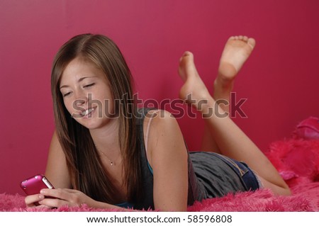 Teenage girl smiles as she checks messages on her cellphone.