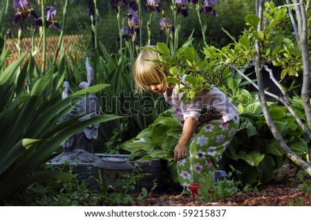 A cute blond girl plays in the garden in the early evening.