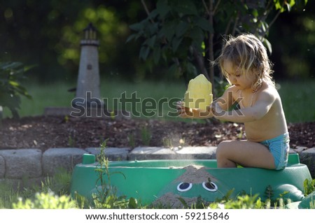 A cute blond girl plays in the garden in the early evening.