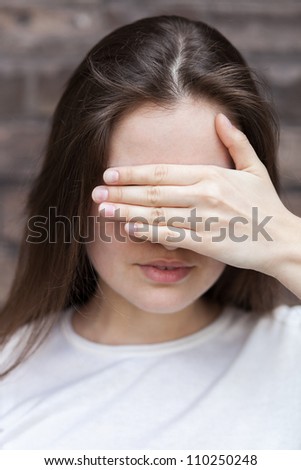 Young woman hides her face palm