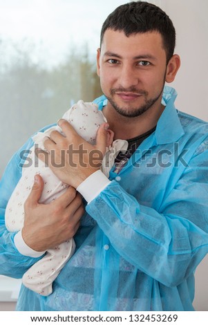 Happy father holding a baby in the maternity ward