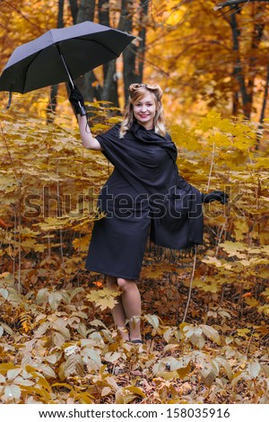 Young woman dressed in black with umbrella in autumn forest
