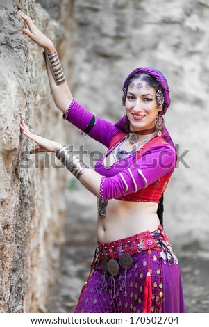 A woman performer of oriental dances in the backdrop of a stone wall