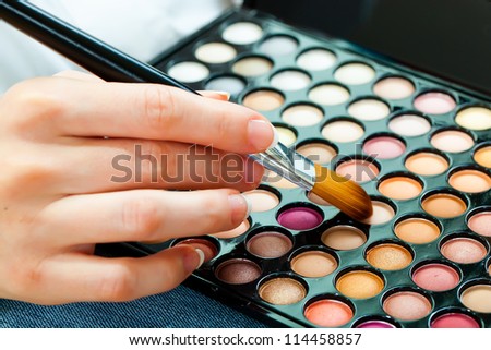 Female hand with makeup brush and paints