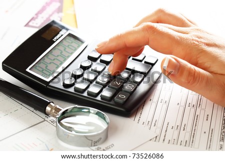 Female  hand  with a calculator and a pen, business  graphics, and  Diagram.