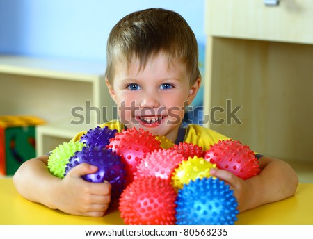 A boy plays with rubber colored balls