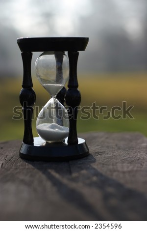 sand clock showing how is time passing, laid on a wood stump