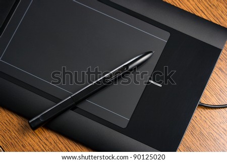 Graphic tablet on wooden table with digital pen