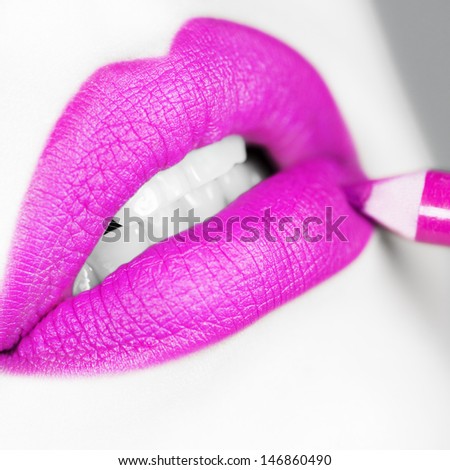 Young woman is doing make up using pink lip liner
