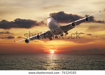 Evening flight. Jet plane over the sea at sunset.