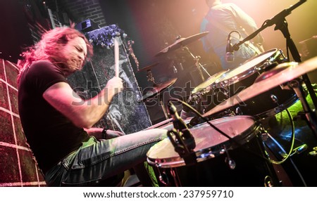 Drummer (blurred motion) playing on drum set on stage. Focus on the drum and microphone. Warning - authentic shooting with high iso in challenging lighting conditions.