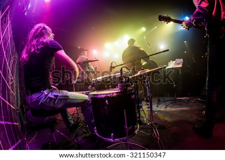 Drummer playing on drum set on stage. Warning - Focus on the drum, authentic shooting with high iso in challenging lighting conditions. A little bit grain and blurred motion effects.