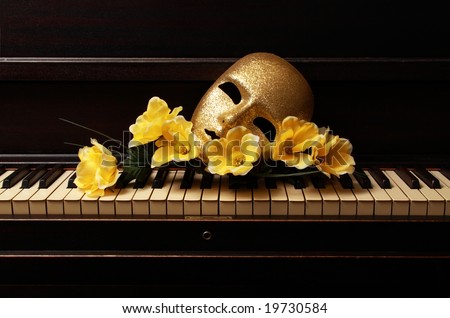 gold mask and yellow flower on a piano