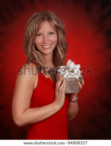 young woman holding a silver gift box with fake white flower, red background