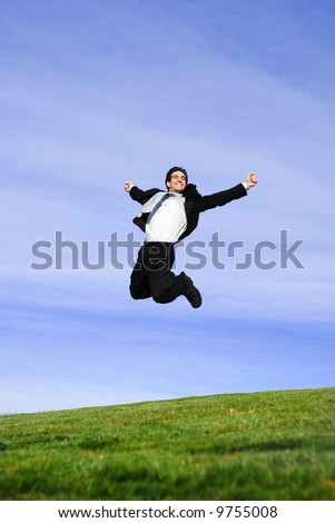 successful and happy young adult businessman running and jumping in the green field