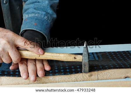 construction worker nailing insulation film on a wooden plank (isolation on black with space for text)