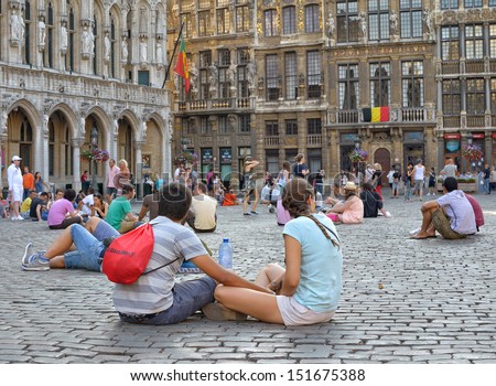 BRUSSELS, BELGIUM - JULY, 21: Tourists follow tradition to sit on Grand Place stones during National Day of Belgium on July 21, 2013 in Brussels. This day Brussels expected 500000 guests