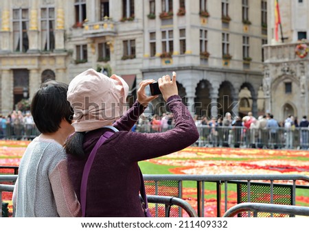 BRUSSELS, BELGIUM-AUGUST 15, 2014: Foreign tourists take pictures of the Flower Carpet. The theme of year 2014 is Persian Carpet or Turkish kilim