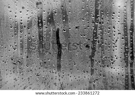 View from a car window during rain with smashed droplets as a weather background. Black and white conversion with filters applied