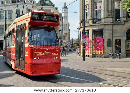 HAGUE, NETHERLANDS-AUGUST 01, 2014: Red tram moves by street in historical center of Hague.