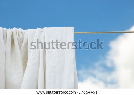 Dried washed bed sheets on rope in bright clear day