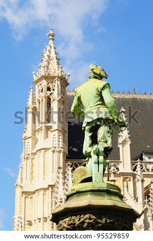 Statue of a warrior in medieval dress watching Petite Sablon church in Brussels, Belgium in bright summer day