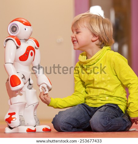 Young child playing with humanoid robot during school time