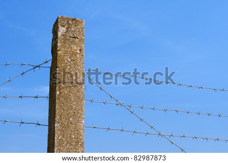 The concrete fence with barbed wire against a blue sky