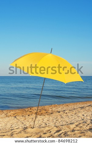 Yellow parasol, standing on the shore of the evening sea