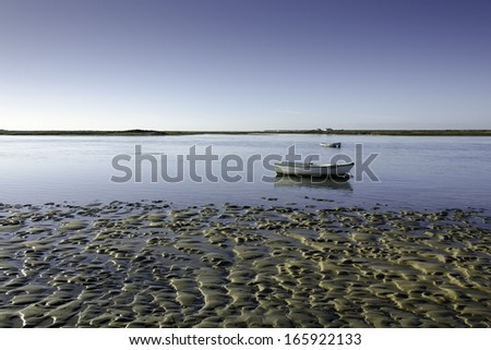 Tidal flat with small boats on a lagoon and water, mud and sand