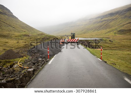 Road construction site on the Faroe Islands with road block sign and digger