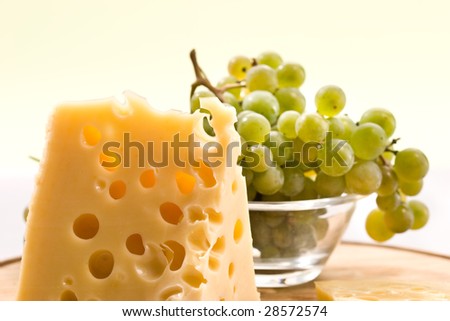 Piece of cheese on the board and grapes
