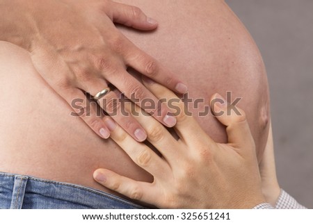 Mother and father holding pregnant belly in third trimester.
