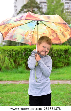 Outdoor portrait of adorable little blond boy with umbrella under the rain
