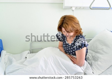 Female patient with abdominal pain on a bed in hospital ward