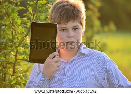 Teen boy with a tablet computer at nature