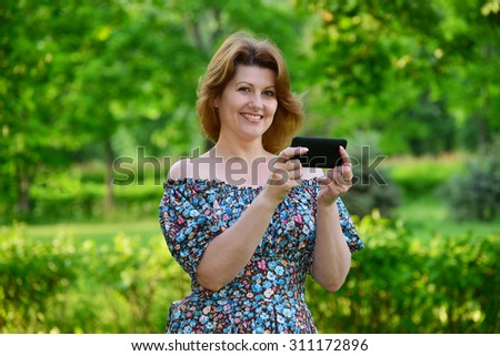 woman with a cell phone in nature in the summer