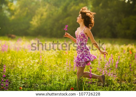 Beautiful young woman running in purple flowers outdoors