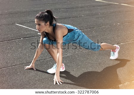Fitness woman getting ready to start running on stadium.