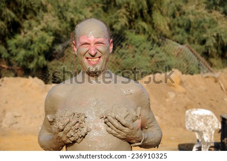 Man applying black healing clay at dead sea Israel
