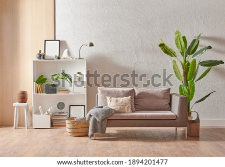 Grey stone wall interior room with wooden decor, bookshelf, sofa and vase of plant, middle table, carpet, home decoration.
