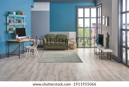Modern television room, blue background, bookshelf on the wall, furniture green and grey sofa, carpet and middle table decoration, interior style.