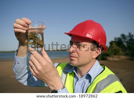 Image of a man holding on to a glass beaker with an environmental sample