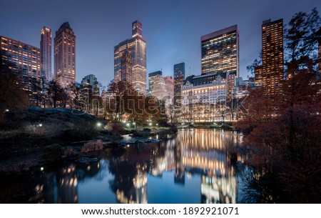 Magical twilight panorama view of New York City Midtown skyline reflecting in the Pond at Central Park South seen from Gapstow Bridge during blue hour at dusk, New York, USA