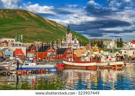 Beautiful view of the historic town of Husavik with traditional colorful houses and traditional fisherman boats lying in the harbor in golden evening light at sunset, northern coast of Iceland Stock foto © 