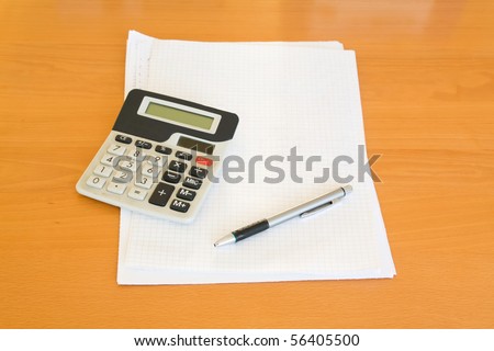 calculator, pen and paper on desk
