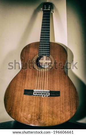 Classical Guitar Leaning. A classical acoustic guitar leaning in a corner, vintage camera effect.